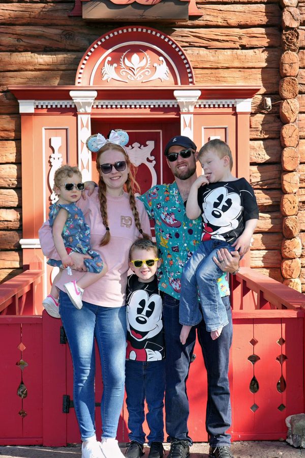 George, his wife and their three kids posed together at a red door during a Disney trip