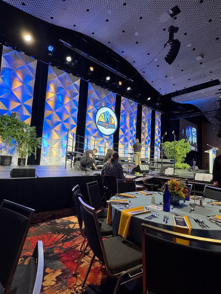 Ballroom stage with a faceted blue and amber scenic wall above round tables
