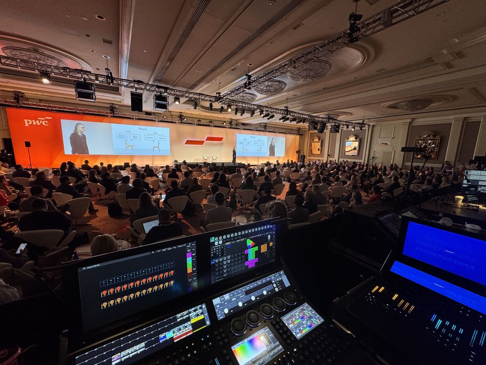 grandMA3 consoles at front of house facing a packed ballroom general session